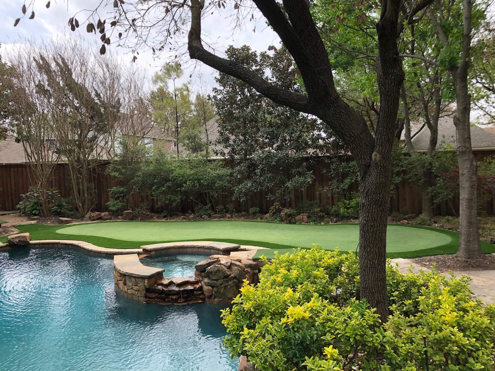 Pool and hot tub next to an artificial grass putting green