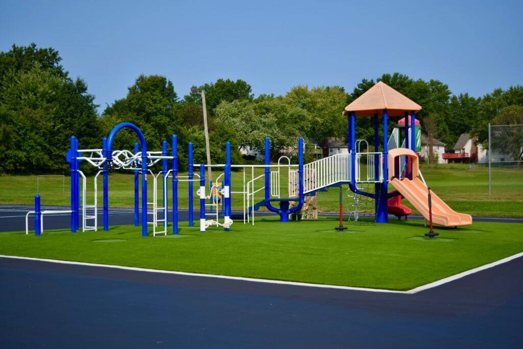 Artificial playground grass with blue jungle gym equipment