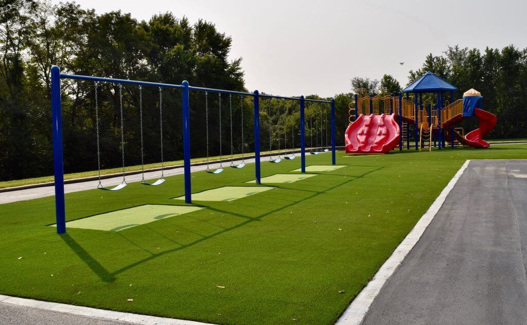 Artificial playground grass with swing set and red slides